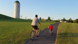 Dad and kid riding bike through Whitestown. Staying active and having fun.